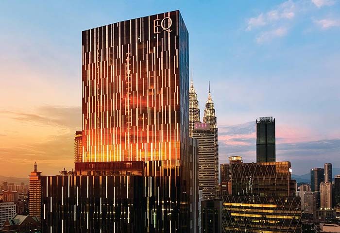 EQ Kuala Lumpur, a gay-friendly hotel. View of the modern building at sunset, with the Petronas Towers in the background. Luxury travel in Malaysia.
