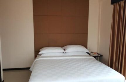 East Hotel, a gay-friendly hotel: Bedroom with a double bed, white sheets, brown headboard, and golden curtains. Simple and clean.
