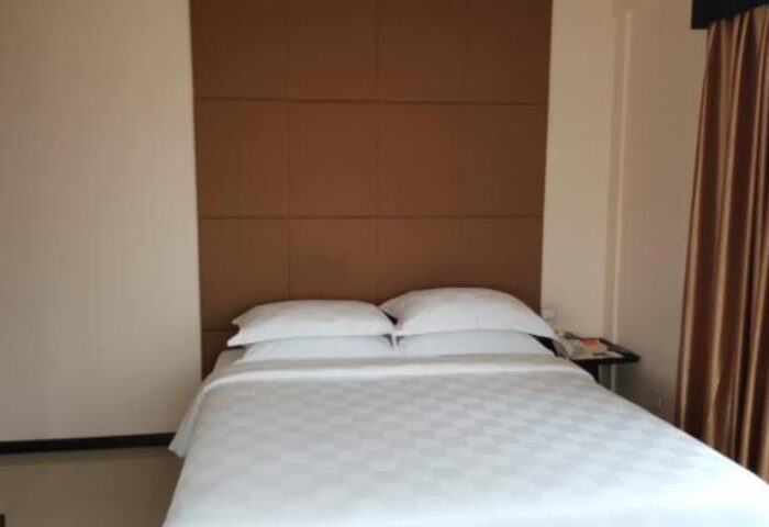 East Hotel, a gay-friendly hotel: Bedroom with a double bed, white sheets, brown headboard, and golden curtains. Simple and clean.