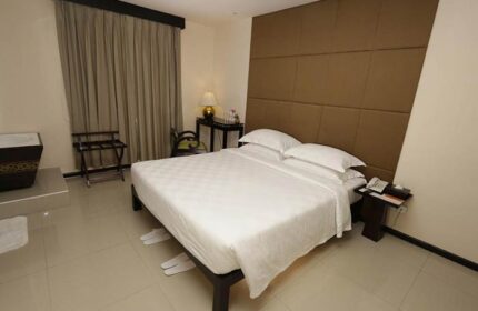 East Hotel's bedroom: Gay-friendly hotel room featuring a double bed with white linens, a brown headboard, and neutral decor. Ideal for gay travel.