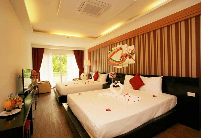 Eclipse Legend Hotel gay-friendly room. Two beds with swan towels and rose petals. Gay travel lodging with striped wall and balcony.