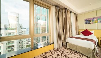 Eco Tree Hotel room. Gay-friendly hotel with city view from large windows. Modern design, single bed, red pillow. Great for gay travel.