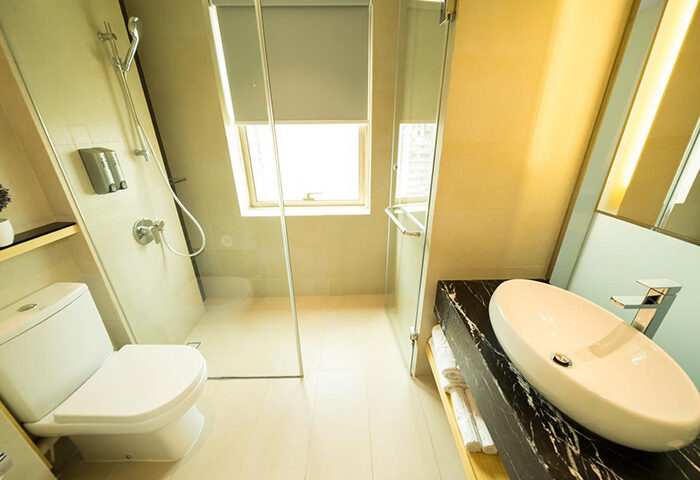 Eco Tree Hotel bathroom. Modern gay-friendly hotel featuring toilet, sink, shower, and window. Clean, well-lit space for a comfortable stay.