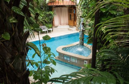 Eco-hotel El Rey del Caribe pool view. Gay-friendly hotel with lush greenery, a dolphin fountain, and a relaxing atmosphere for gay travelers.