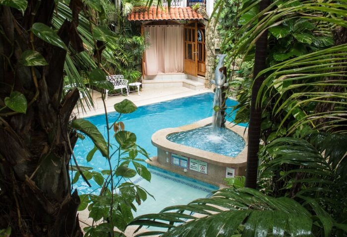 Eco-hotel El Rey del Caribe pool view. Gay-friendly hotel with lush greenery, a dolphin fountain, and a relaxing atmosphere for gay travelers.