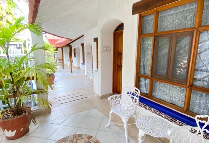 Eco-hotel El Rey del Caribe's gay-friendly patio. White chairs, tiled floor, and lush plants create a welcoming space in this Caribbean hotel.