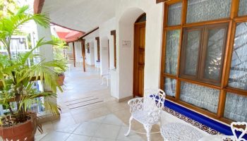 Eco-hotel El Rey del Caribe's gay-friendly patio. White chairs, tiled floor, and lush plants create a welcoming space in this Caribbean hotel.
