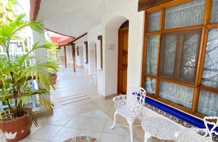 Eco-hotel El Rey del Caribe's gay-friendly patio. White chairs, tiled floor, and lush plants create a welcoming space in this Caribbean hotel.
