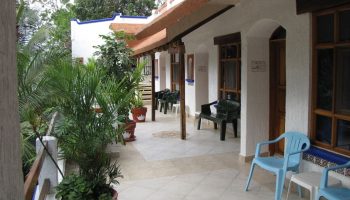El Rey del Caribe eco-hotel patio. Gay-friendly hotel with chairs outside rooms. Tropical plants add to the Caribbean vibe.