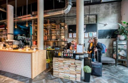 Ecomama Hotel's stylish lobby. Gay-friendly hotel with industrial design, books, and a cafe. Travelers with luggage check-in. Amsterdam travel.