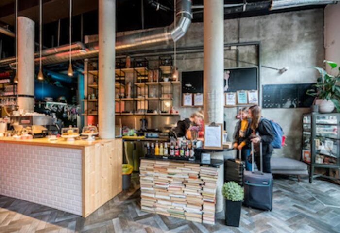 Ecomama Hotel's stylish lobby. Gay-friendly hotel with industrial design, books, and a cafe. Travelers with luggage check-in. Amsterdam travel.