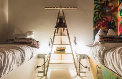 Ecomama Hotel's gay-friendly room: twin beds, ladder nightstand with a doll, books, & lamps. Graffiti art adds flair to this unique hotel room.