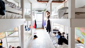 Ecomama Hotel gay-friendly hostel dorm. Bunk beds in a shared room. Travelers relaxing. Budget-friendly accommodation for gay men travel.