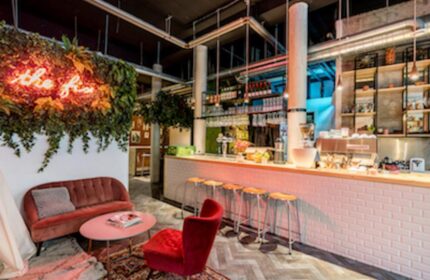Ecomama Hotel's stylish bar area. Gay-friendly hotel with a cozy lounge, bar stools, and neon sign. Interior design for gay men travel.
