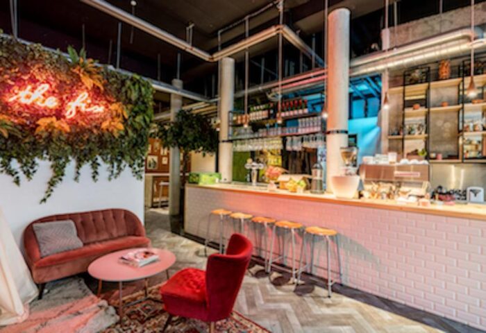 Ecomama Hotel's stylish bar area. Gay-friendly hotel with a cozy lounge, bar stools, and neon sign. Interior design for gay men travel.
