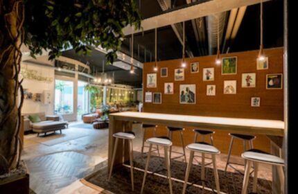 Ecomama Hotel's interior: A gay-friendly hotel with a communal table, stools, and art. Inviting space for gay men travel.