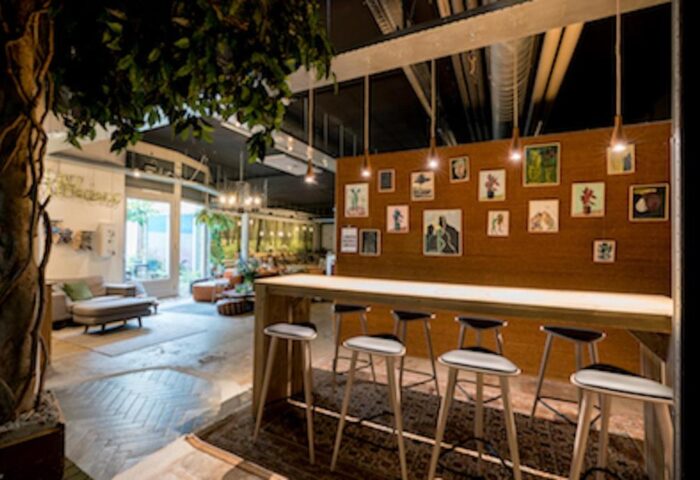 Ecomama Hotel's interior: A gay-friendly hotel with a communal table, stools, and art. Inviting space for gay men travel.