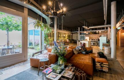 Ecomama Hotel's gay-friendly interior. A man relaxes on a brown leather couch. The hotel's common area is stylish and inviting. Travel advice.