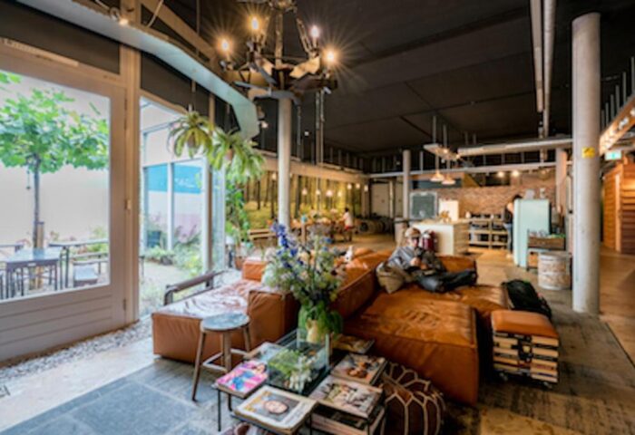 Ecomama Hotel's gay-friendly interior. A man relaxes on a brown leather couch. The hotel's common area is stylish and inviting. Travel advice.