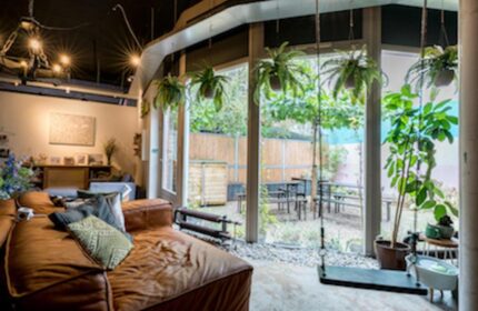 Ecomama Hotel's gay-friendly vibe: Cozy lounge with leather couch, plants, and a swing. View to the garden. Interior design.