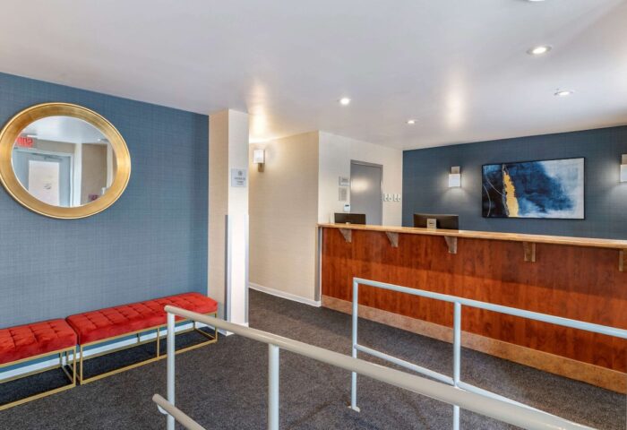 Econo Lodge gay-friendly hotel lobby. Reception desk, red benches, and a round mirror. A welcoming space for gay travelers.