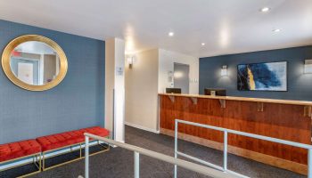 Econo Lodge gay-friendly hotel lobby. Reception desk, red benches, and a round mirror. A welcoming space for gay travelers.