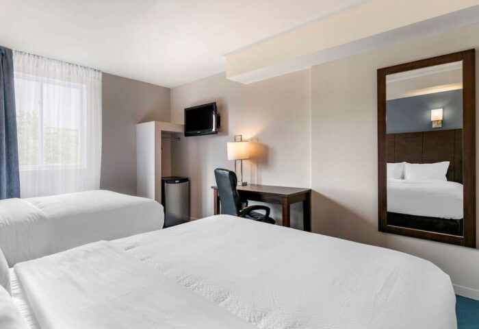 Econo Lodge gay-friendly hotel room with two beds, desk, mini fridge, and TV. Comfortable stay for gay men travelers.