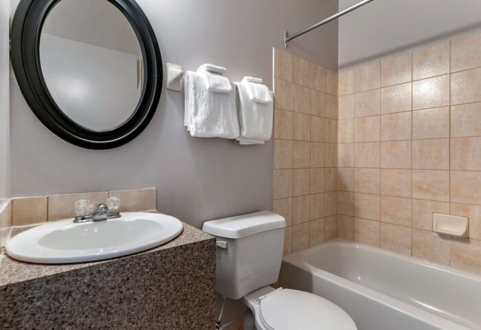 Econo Lodge gay-friendly hotel bathroom. Sink, mirror, towels, toilet, and tiled shower/bathtub combo. Gay travel lodging option.