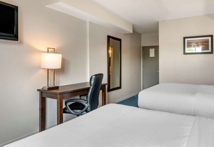 Econo Lodge gay-friendly hotel room. Two beds, a desk with a lamp, a chair, a mirror, and a TV. Comfortable stay for gay travelers.