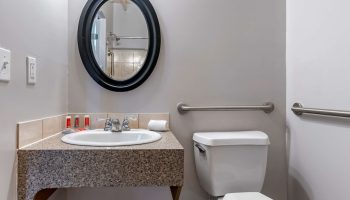 Econo Lodge gay-friendly hotel bathroom. Sink, oval mirror, toilet with grab bars. Accessible design for LGBTQ+ travelers.