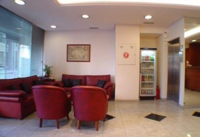 Lobby area at a gay-friendly economy hotel. Red sofas and chairs, drinks fridge, and elevator. A comfortable space for gay travelers.