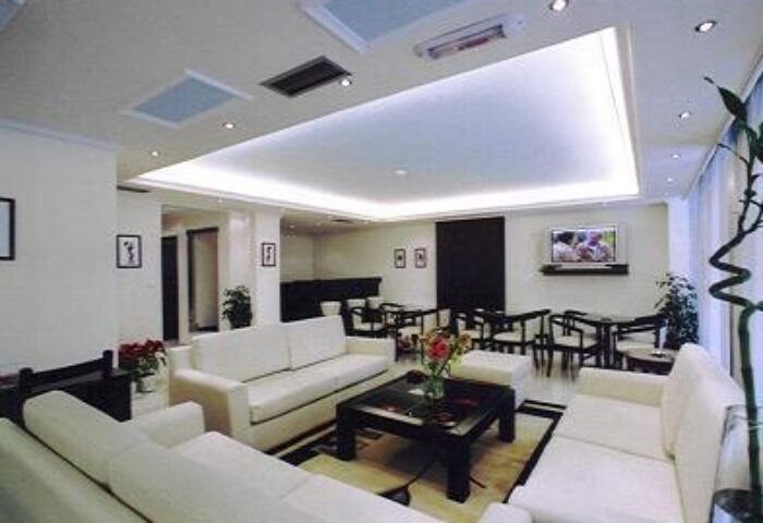 Gay-friendly economy hotel lounge area. White sofas, dark wood tables, and a TV. Modern design for gay travelers.
