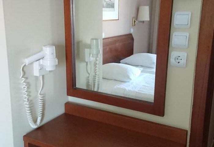 Economy Hotel room's vanity with mirror, stool, and hairdryer. Gay-friendly hotel with essential amenities for gay men travelers.