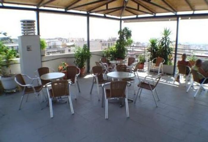 Rooftop terrace at a gay-friendly economy hotel. Tables and chairs under a canopy, with city views. Great for gay men travelers.