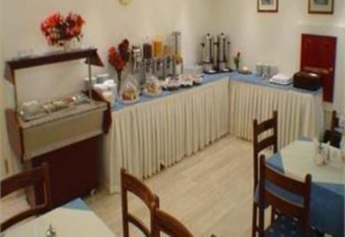 Breakfast buffet at a gay-friendly economy hotel. Food selection includes juice, coffee, pastries, and hot dishes. Tables and chairs nearby.