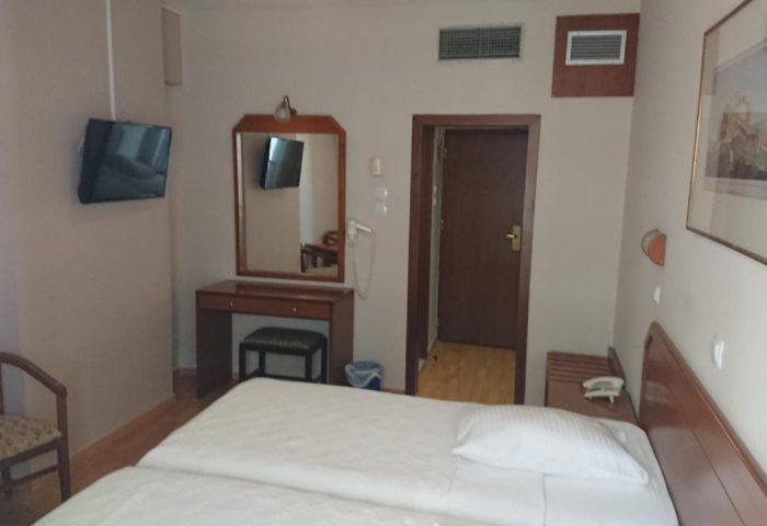 Economy Hotel room with twin beds, desk, chair, and TV. Gay-friendly hotel option for budget travelers.