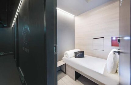 Eighteen By Three Cabins interior. A single bed in a modern, minimalist cabin. Gay-friendly hotel room. Clean, compact design. Travel lodging.