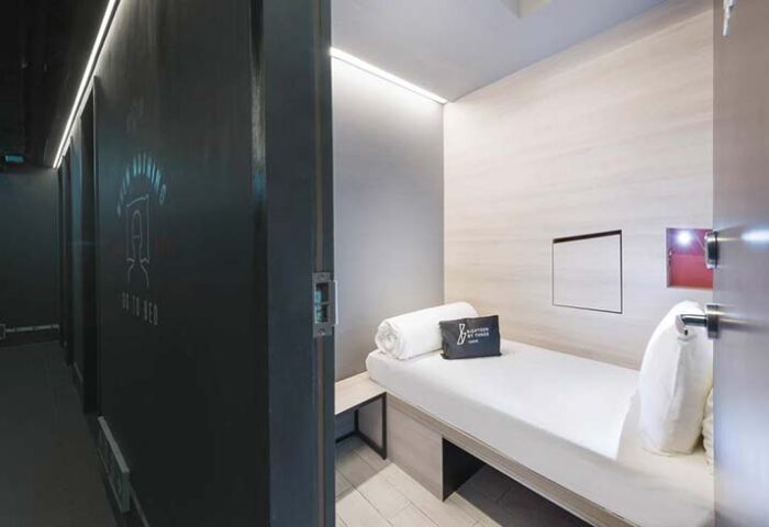 Eighteen By Three Cabins interior. A single bed in a modern, minimalist cabin. Gay-friendly hotel room. Clean, compact design. Travel lodging.