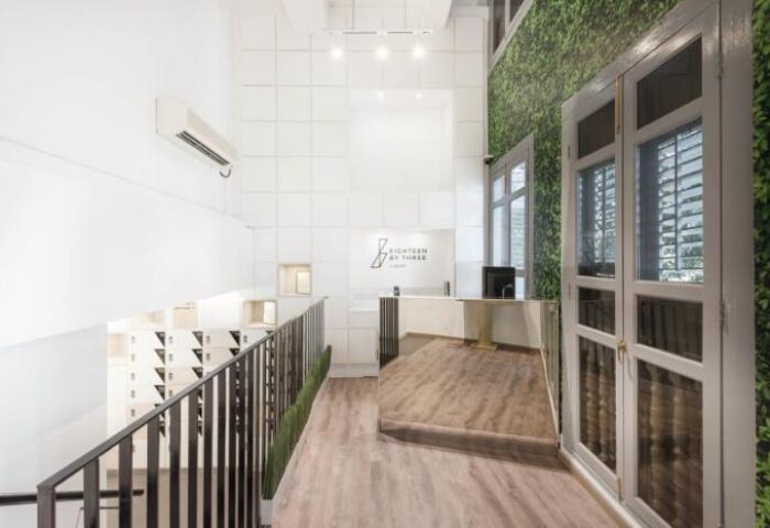 Eighteen By Three Cabins' lobby. This gay-friendly hotel features a modern design with white walls, wood floors, and a green wall. Great for gay travel.