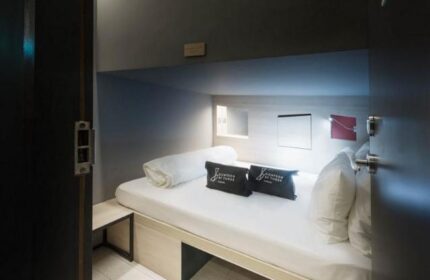 Eighteen By Three Cabins interior. Gay-friendly hotel cabin with bed, pillows, and storage. Modern, minimalist design for gay men travelers.