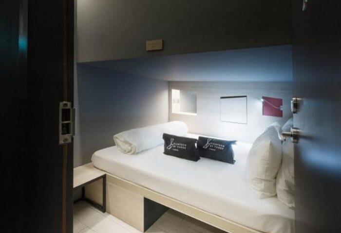 Eighteen By Three Cabins interior. Gay-friendly hotel cabin with bed, pillows, and storage. Modern, minimalist design for gay men travelers.