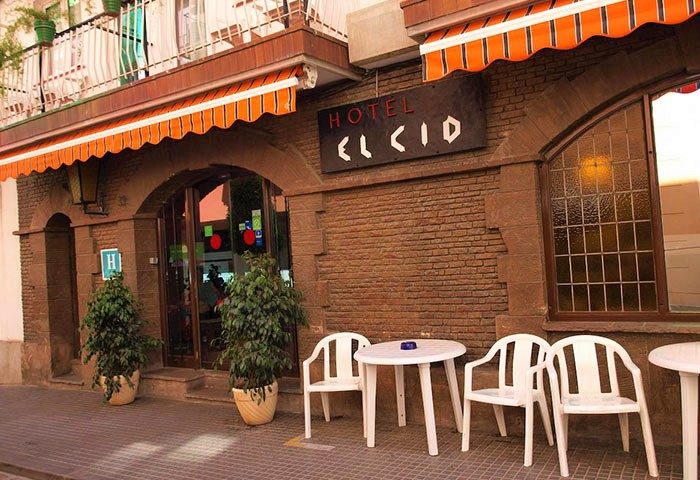 Hotel El Cid, a gay-friendly hotel. Exterior view of the hotel, with tables and chairs outside. A welcoming space for gay travelers.