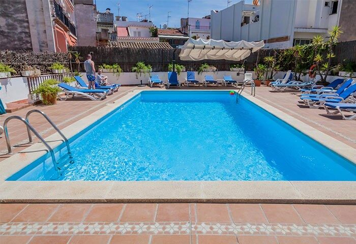 El Cid Gay-Friendly Hotel pool view. Outdoor swimming pool with clear blue water, surrounded by sun loungers. Gay travel advice.