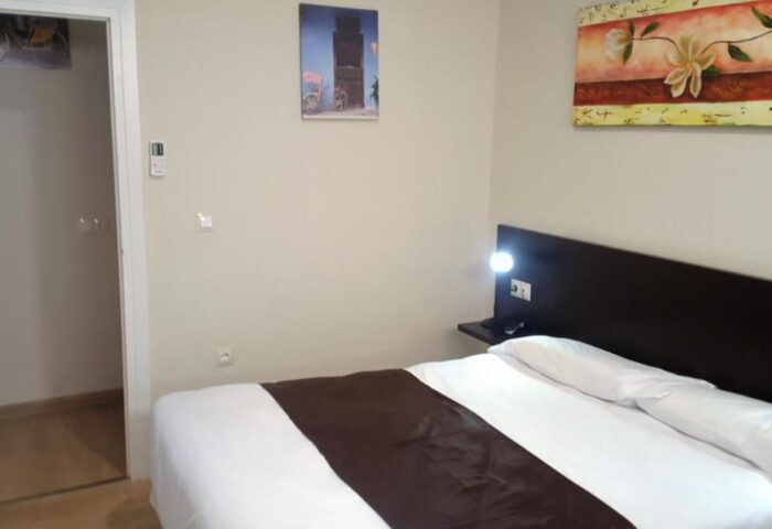 El Pozo gay-friendly hotel room. Clean, simple decor. Comfortable bed with brown accent. An ideal stay for gay travelers.