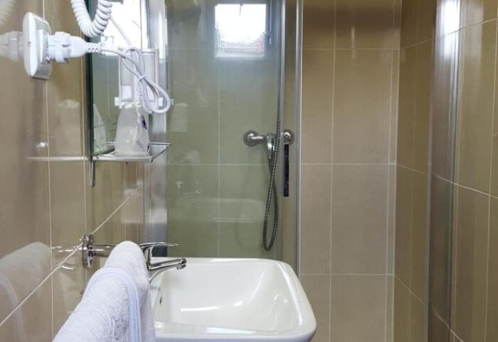 Bathroom at El Pozo, a gay-friendly hotel. Features include a shower, sink, hair dryer, and neutral tile. Ideal for gay travel.