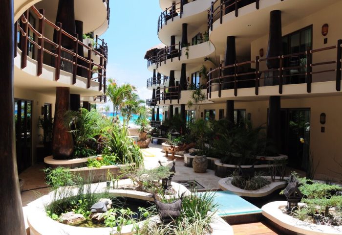 El Taj Oceanfront Condo Hotel courtyard view. Gay-friendly beachside hotel with lush gardens, pools, and ocean views. Playa del Carmen travel.