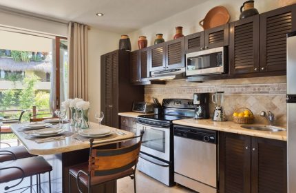 El Taj Oceanfront Condo Hotel kitchen. Gay-friendly hotel with modern appliances, dining table, and balcony view. Beachside condo living.