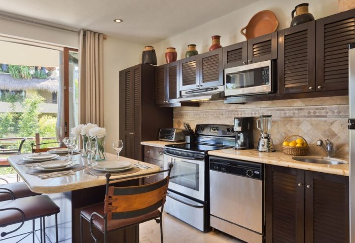 El Taj Oceanfront Condo Hotel kitchen. Gay-friendly hotel with modern appliances, dining table, and balcony view. Beachside condo living.