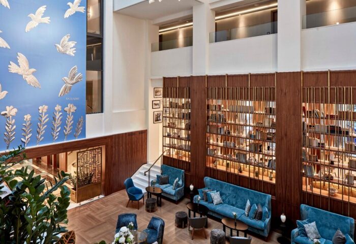 Electra Metropolis Hotel's stylish lobby. This gay-friendly hotel features a library wall, blue sofas, and bird art. Perfect for gay travel.