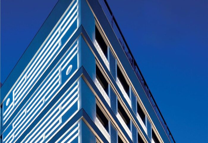 Electra Metropolis Hotel facade. The gay-friendly hotel features a modern design with blue and white geometric patterns against a clear blue sky.